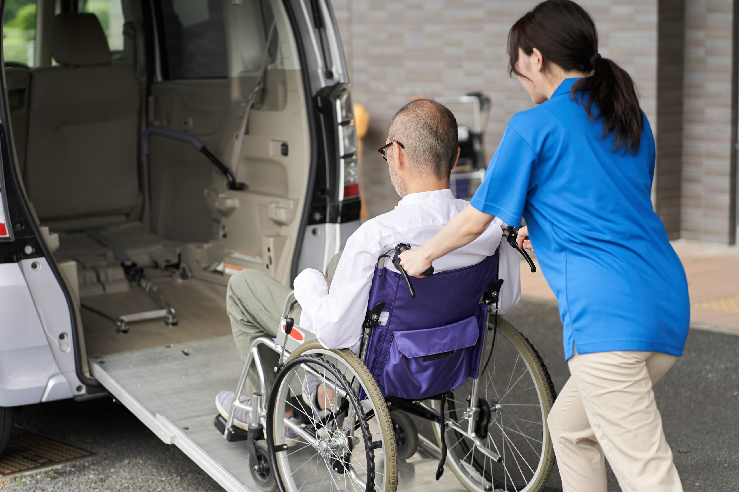 Caregiver assisting elderly patient into NEMT van for medical appointment in Virginia